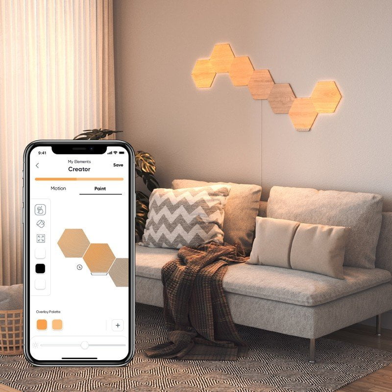 Nanoleaf Elements Hexagons mounted on a wall in a living room with the Nanoleaf application displayed on a phone